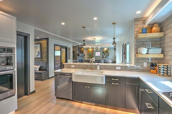 A modern kitchen with a central island, built-in appliances, and pendant lighting.