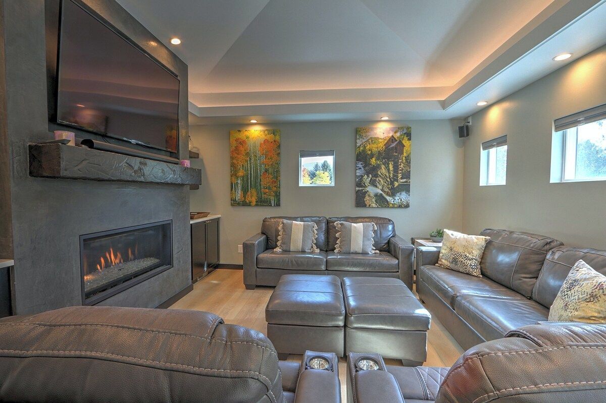 A modern living room with a fireplace, leather sofas, and artwork on the walls.