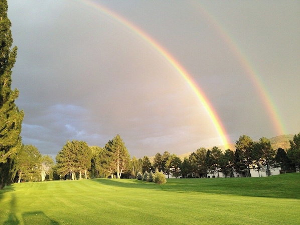A golf course with a rainbow in the sky.