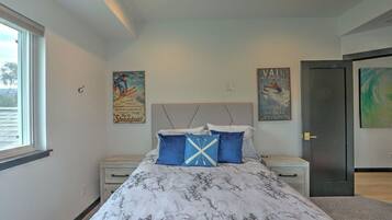 A bedroom with a bed, nightstands, a window, and two posters on the wall.