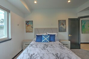 A bedroom with a bed, nightstands, a window, and two posters on the wall.
