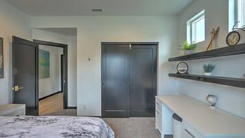 A bedroom with a bed, a wardrobe, a dresser, and a shelf with decorative items.