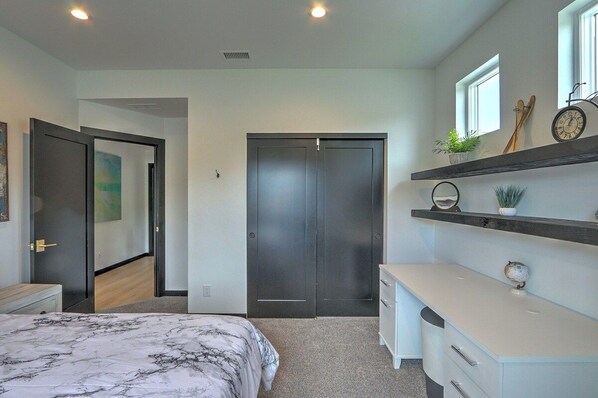 A bedroom with a bed, a wardrobe, a dresser, and a shelf with decorative items.