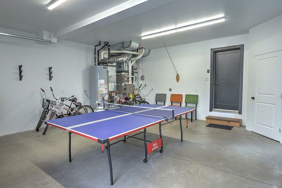 A ping pong table in a room with a door, a bicycle, and a wall-mounted air conditioning unit.