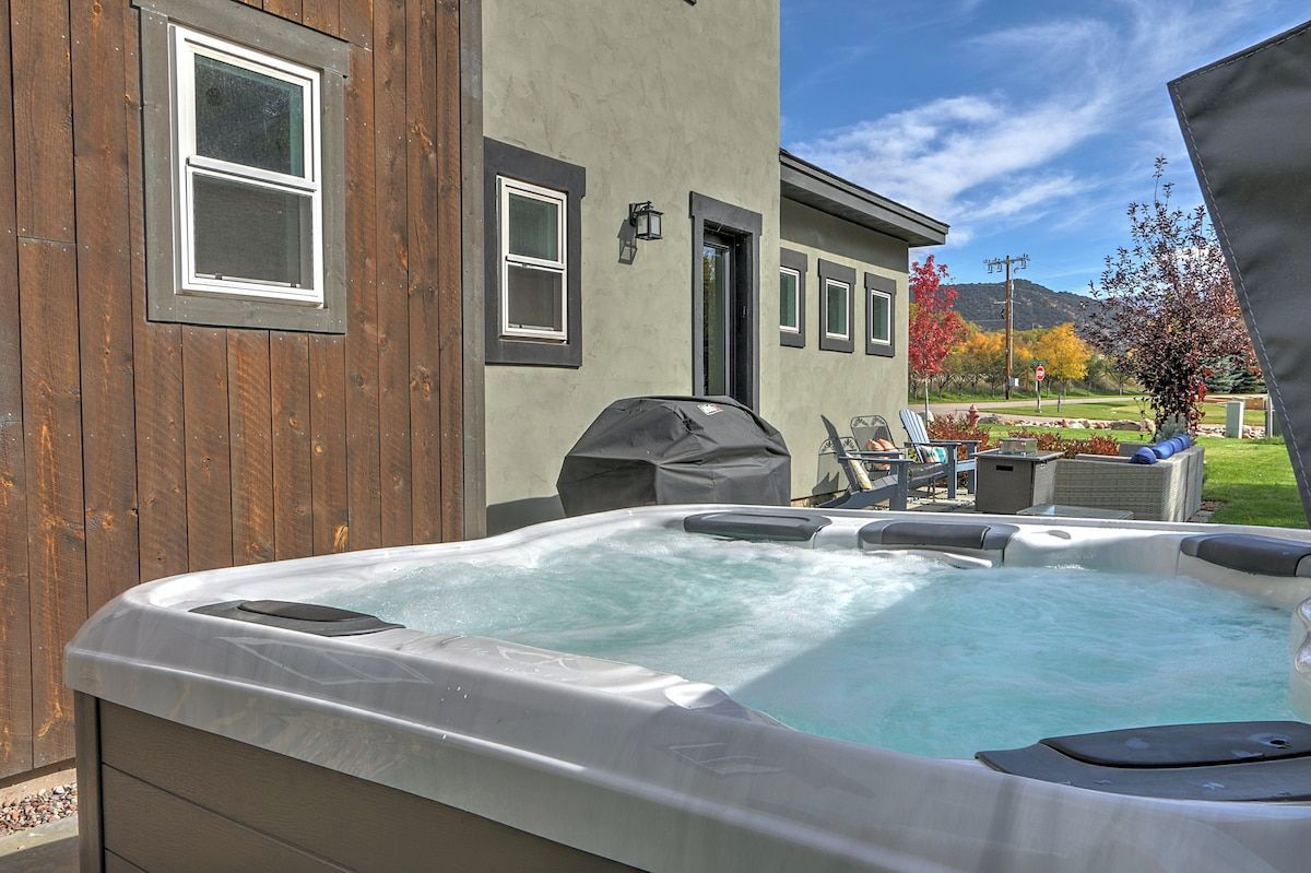 Un jacuzzi en un patio trasero con una valla de madera y una casa al fondo.