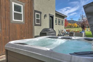 Un jacuzzi dans un jardin, avec une clôture en bois et une maison en arrière-plan.