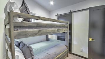 A bunk bed with a wooden frame and grey bedding, a wardrobe with a sliding door, and a door with a handle.