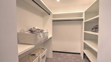 A walk-in closet with shelves, a hanging rod, and a storage bin.