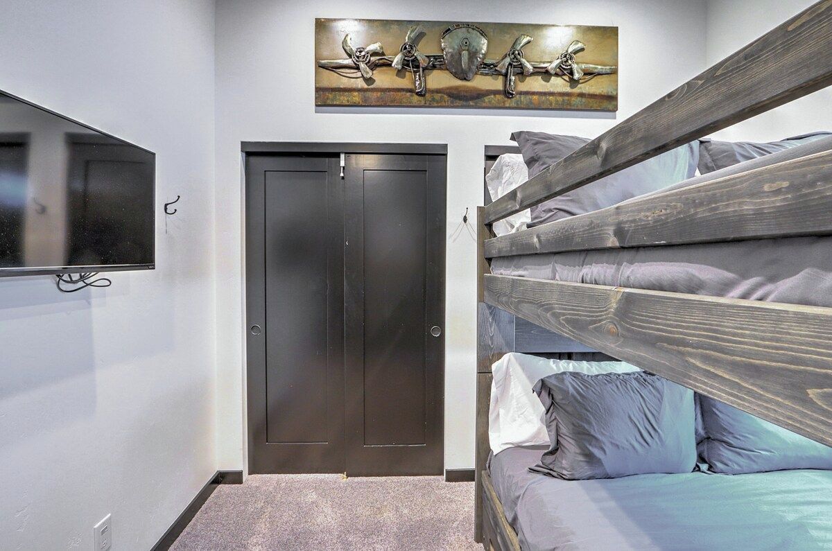 Une chambre avec un lit superposé, une porte, un téléviseur à écran plat fixé au mur et une œuvre d’art décorative au-dessus de la porte.