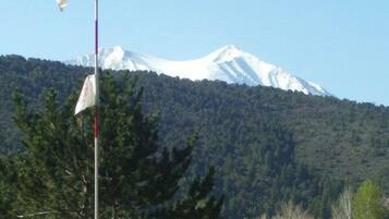 A golf flag on a flagpole with a mountain in the background.
