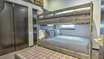 A bunk bed with a plaid-patterned mattress, a wooden headboard, and a window above.