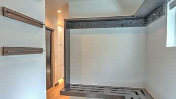A corner of a room with a built-in bench, a coat rack, and a door.