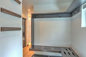 A corner of a room with a built-in bench, a coat rack, and a door.