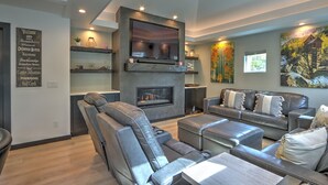 Ein modernes Wohnzimmer mit Kamin, Ledersofas und einem großen Fernseher.