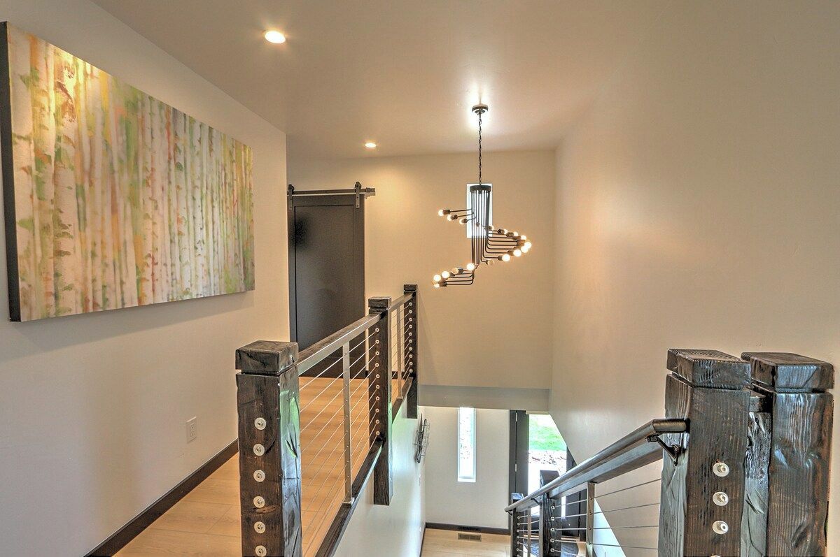 A modern interior with a wooden staircase, a hanging light fixture, and a large abstract painting on the wall.