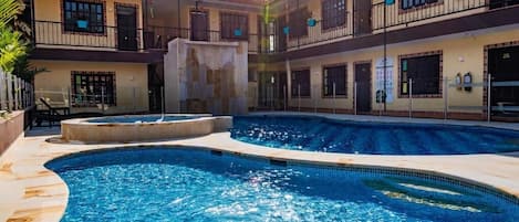 Una piscina de diseño curvo, rodeada por un edificio con múltiples balcones y ventanas.