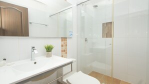 Un baño moderno con un lavabo blanco, un espejo, cabina de ducha de cristal y un inodoro.