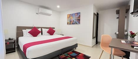 Una habitación de hotel moderna con una cama grande, un escritorio y un tapete colorido.