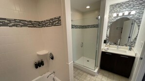 A modern bathroom with a bathtub, a shower enclosure, and a vanity with a mirror. - Pet friendly hotel aprt on Celebration Pl. 2bdr (Celebration)