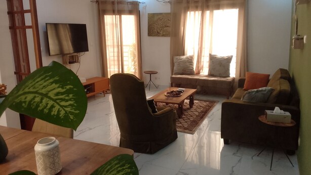Una sala de estar con sofá, sillón, mesa de centro y televisor.
