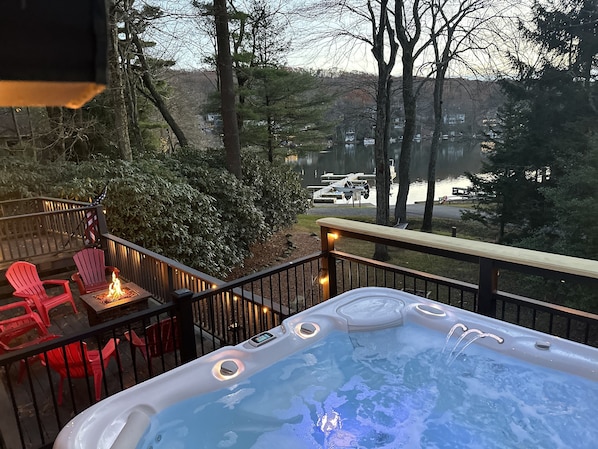 Un jacuzzi en una terraza con vista a un lago y barcos amarrados.