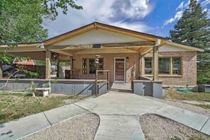 A two-story house with a covered porch, a front door, and a small front yard. - Red Rock Farmhouse! Hot Tub, Fire Pit & Trails (Colorado Springs)