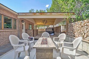 An outdoor patio with a fire pit table, white plastic chairs, and a pergola structure. - Red Rock Farmhouse! Hot Tub, Fire Pit & Trails (Colorado Springs)