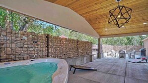 A covered outdoor area with a hot tub, stone wall, and patio furniture. - Red Rock Farmhouse! Hot Tub, Fire Pit & Trails (Colorado Springs)