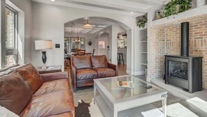 A modern living room with leather sofas, a glass coffee table, and a fireplace. - Red Rock Farmhouse! Hot Tub, Fire Pit & Trails (Colorado Springs)