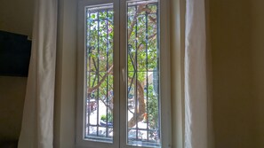 A window with a view of a tree and a metal gate outside. - Casa Monte Victoria (Málaga)