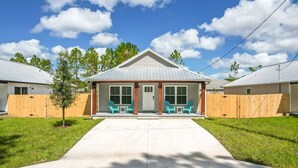 A two-story house with a front porch, a small tree, and a wooden fence. - SunRise Cottage: 3 Bed/2 Bath - Centrally Located! (St. Augustine)