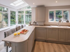 Een moderne keuken met een ontbijtbalk, grote ramen en uitzicht op groen.