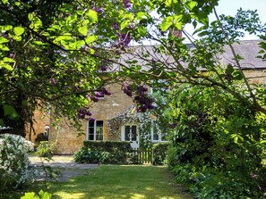 A stone building with a garden, a wooden fence, and a clear sky.
