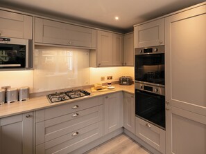 Une cuisine moderne équipée d’une cuisinière à gaz, d’un four, d’un grille-pain et d’un four à micro-ondes encastré.
