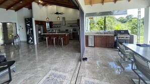 A spacious kitchen with a large island, modern appliances, and a view of lush greenery. - Casa Hacienda Jaguar (Ciudad Cortés)