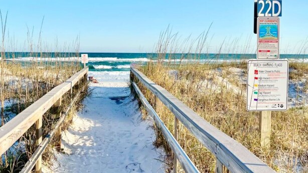 A wooden boardwalk leading to a beach with a warning sign about rip currents. - Sand Dollar W212 Bayfront Escape- Gorgeous Sunset Views, Bikes Included! (Pensacola Beach)