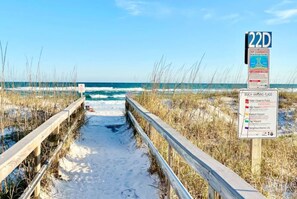 A wooden boardwalk leading to a beach with a warning sign about rip currents. - Sand Dollar W212 Bayfront Escape- Gorgeous Sunset Views, Bikes Included! (Pensacola Beach)