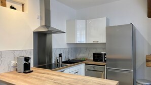 Una cocina moderna con encimera de madera, electrodomésticos de acero inoxidable y armarios blancos.