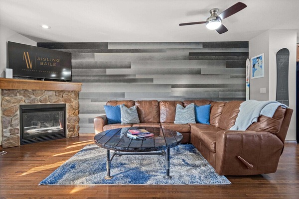 Living room with a Smart TV, cozy reclining sofa and a decorative fireplace (please note it is on-functional)