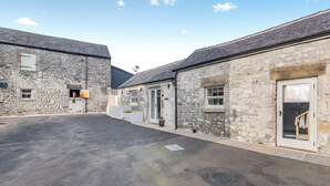 A stone building with a large open driveway, a horse stable, and a small window. - 1 bedroom accommodation in Chelmorton (Chelmorton)