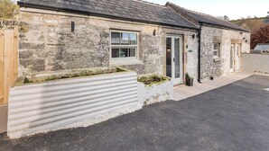 A stone building with a sloped roof, a front door, and a small window. - 1 bedroom accommodation in Chelmorton (Chelmorton)