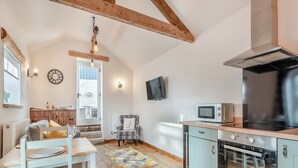 A compact kitchen with a microwave, stove, and wooden ceiling beams. - 1 bedroom accommodation in Chelmorton (Chelmorton)
