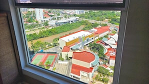 Vista desde una ventana sobre un paisaje urbano con edificios, un río y un complejo deportivo.