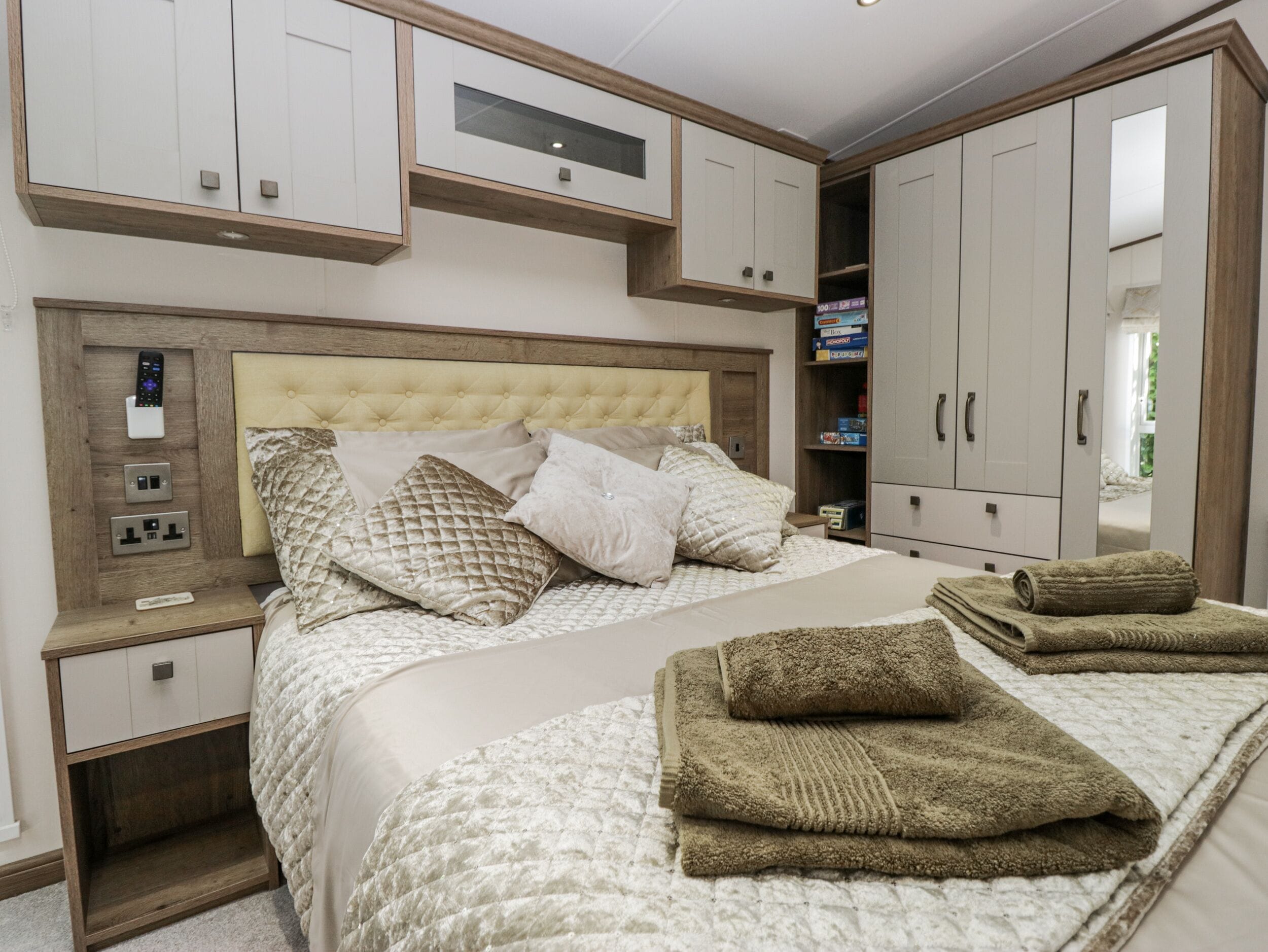 A bedroom with a large bed, a nightstand, a wardrobe, and a mirror.