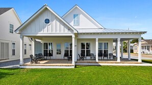 A two-story house with a covered porch and a stone patio. - New 3 Bedroom Beachfront Rental in downtown Bay St Louis (Bay St. Louis)