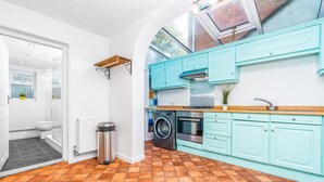 Una cocina con gabinetes azul turquesa, una lavadora y una estufa.