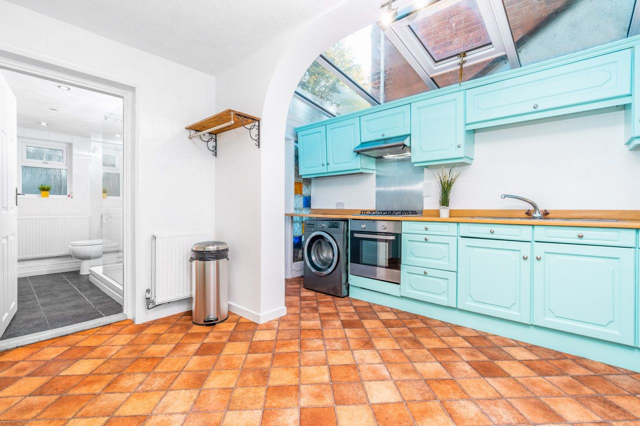 A kitchen with teal cabinets, a washing machine, and a stove.