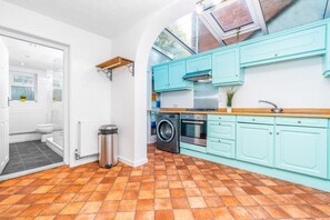 A kitchen with teal cabinets, a washing machine, and a stove. - Stylish Three Bedroom House - Harborne - Parking - Garden (Harborne)