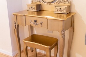 A vintage-style vanity with a mirror and two drawers, accompanied by a matching stool.