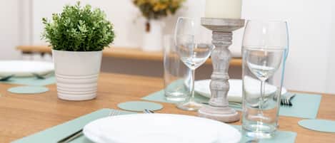 A neatly set dining table with white plates, clear glasses, and a candle holder.